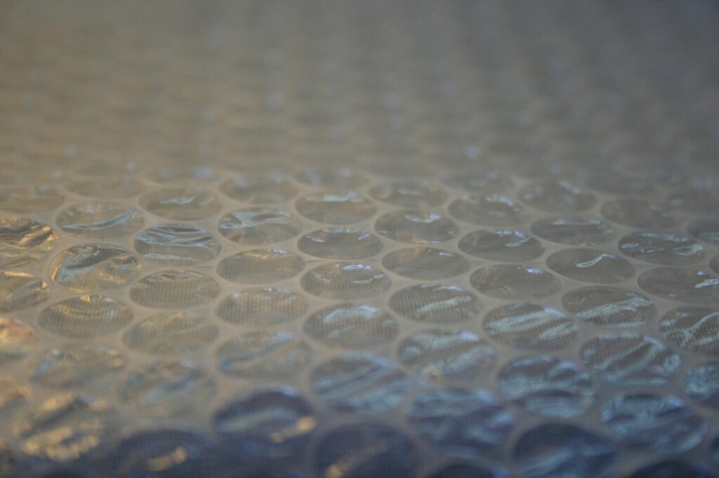 woman applying bubble wrap insulation film on window