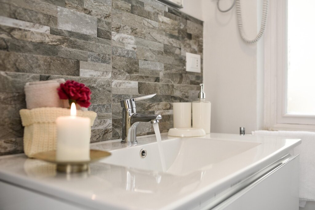 bathroom faucet with white limescale deposits being cleaned with vinegar soaked paper towel