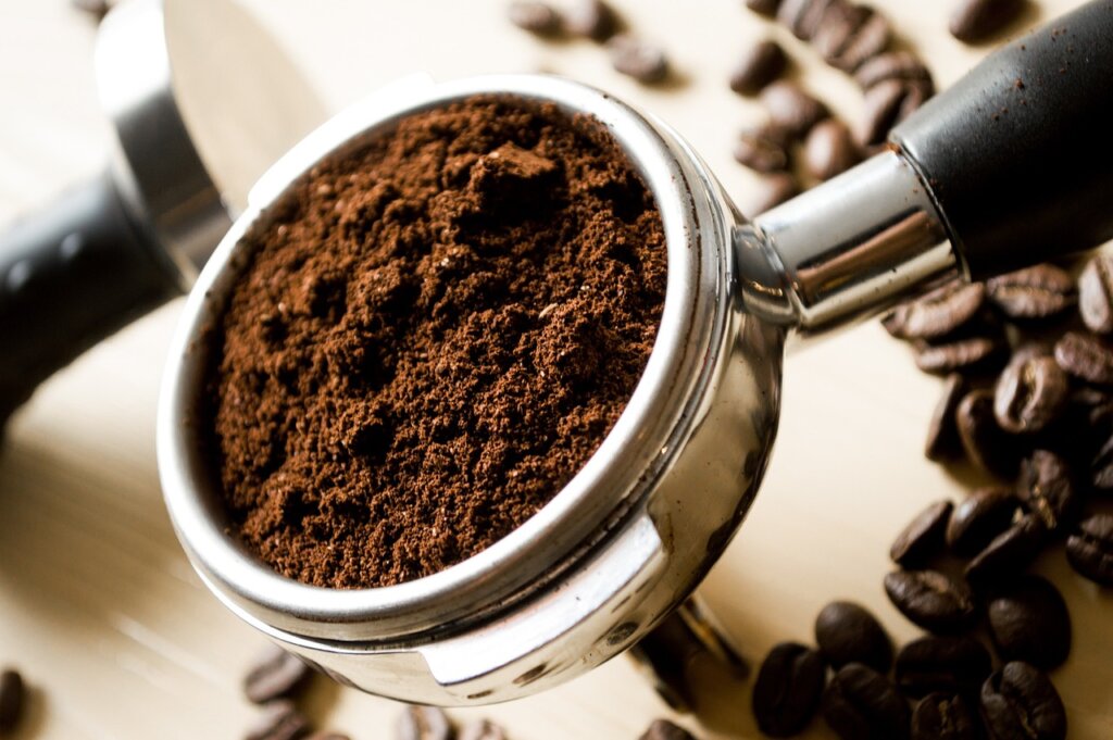 coffee grounds sprinkled in a small kitchen waste bin beside baking soda box, top view