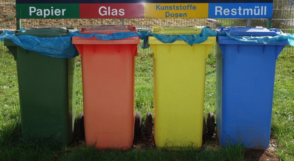 sorted recycling bins with labels for plastic, paper, vinyl and cans outdoors
