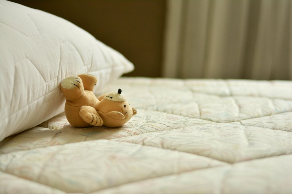 white mattress protector being fitted onto a mattress with zipper closure detail