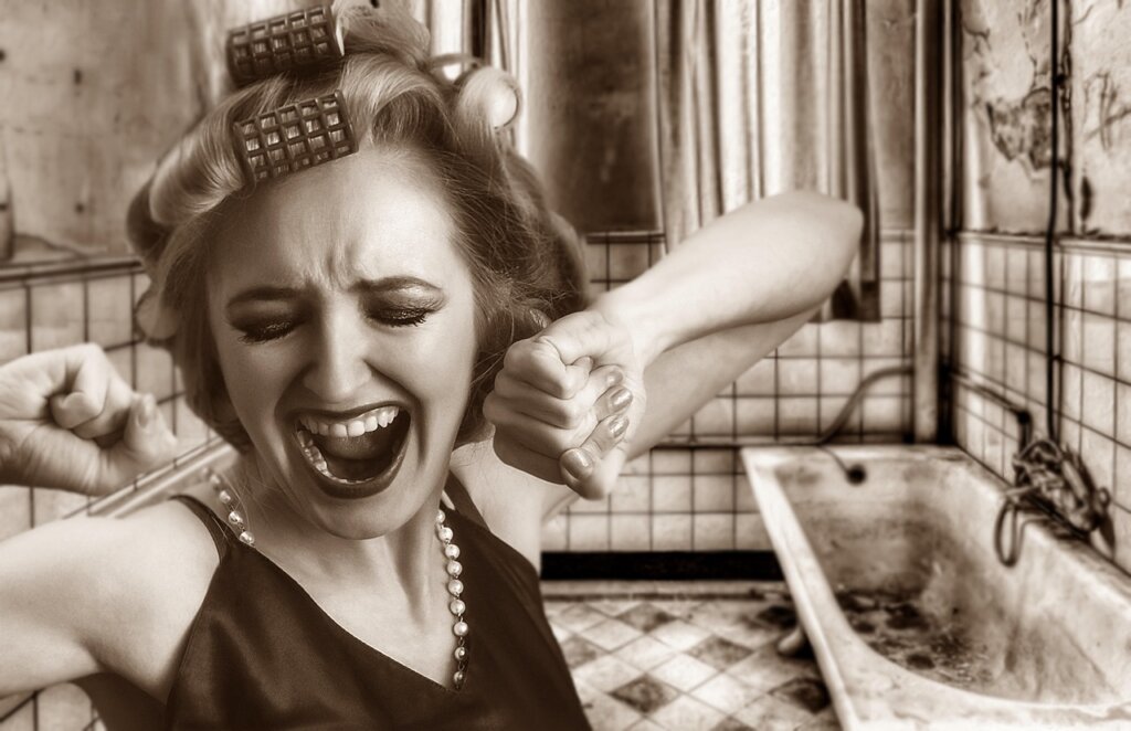 person scrubbing bathroom tile grout with old toothbrush and citric acid solution