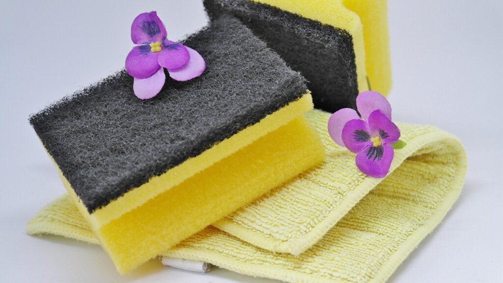 cream cleanser being applied with sponge to bathtub grout area