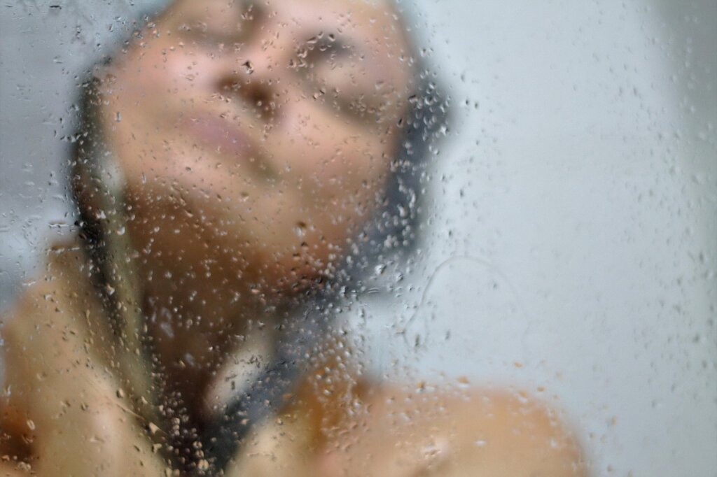 squeegee wiping water from glass shower door