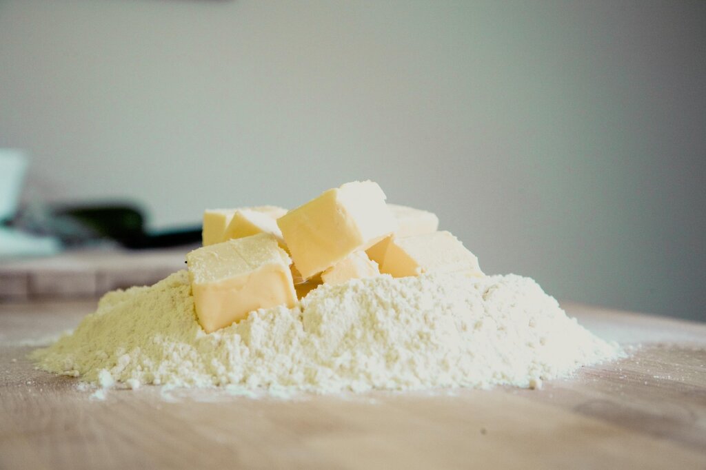 baking soda powder sprinkled on green kitchen sponge on white tile